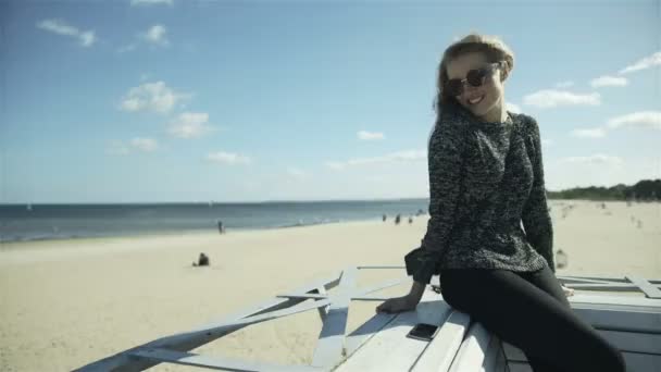 Ung glad kvinna med solglasögon njuta av vackert väder på stranden. — Stockvideo