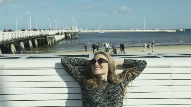 Gelukkig jongedame met zonnebril genieten van mooie weer op het strand. — Stockvideo