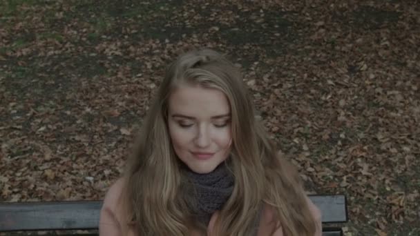 Pretty  woman sitting on a bench in a park waiting for someone. Closeup. — Stock Video