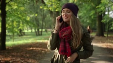 Sonbahar parkta cep telefonuyla konuşan genç şık kadın.