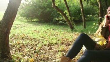 Dinlenme ve yanında smartphone parkta ağaç altında söz kadın.