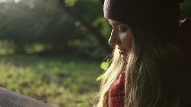 Nahaufnahme eines schönen jungen kaukasischen Mädchens, das im Herbst im Park ein Buch liest. — Stockvideo