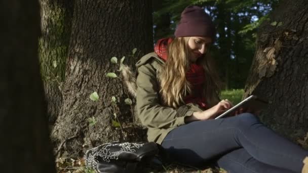 Jonge vrouw met tablet pc in mooie herfst park. — Stockvideo