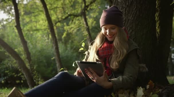 平板电脑在美丽的秋天公园的年轻女子. — 图库视频影像