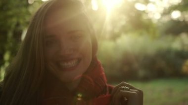 Sonbahar parkta gülümseyen genç sarışın kadın.