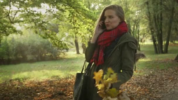 Glad ung kvinna talar i mobiltelefon i höst park. — Stockvideo