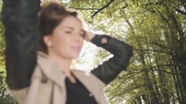 Sonbahar parkta gülümseyen düşünceli şık kadın.