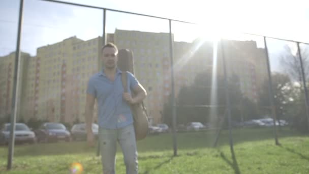 Retrato de jovem atraente homem com guitarra em pé perto de uma cerca de metal . — Vídeo de Stock