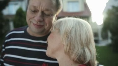 Mutlu olgun çift ayakta--dan onların ev ve kameraya bakıyor.