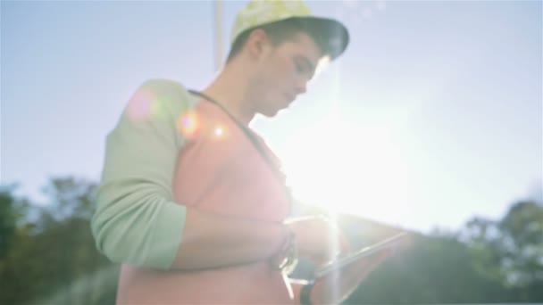 Joven adolescente con estilo utilizando la tableta en una calle de la ciudad durante el día soleado . — Vídeo de stock