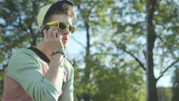 Portret van een stijlvolle vrolijke jongen praten over telefoon, buitenshuis. — Stockvideo