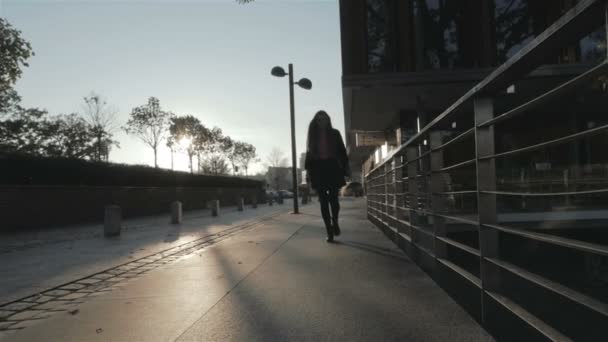 Silhouet van jong meisje vreugdevol wandelen in de straten van de stad, slow-motion. — Stockvideo