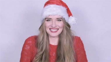 Beyaz arka plan üzerinde bir öpücük gönderme Noel şapkalı çekici genç kadın.