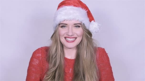 Привлекательная молодая женщина в рождественской шляпе посылает поцелуй на белом фоне . — стоковое видео