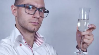 Genç yakışıklı adam beyaz gömlekli kutlamak şampanya ile gri arka plan üzerinde.