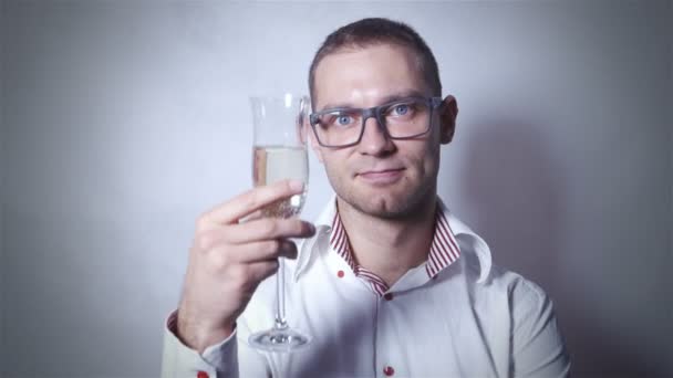 Joven hombre guapo en camisa blanca celebrar con champán sobre fondo gris . — Vídeos de Stock