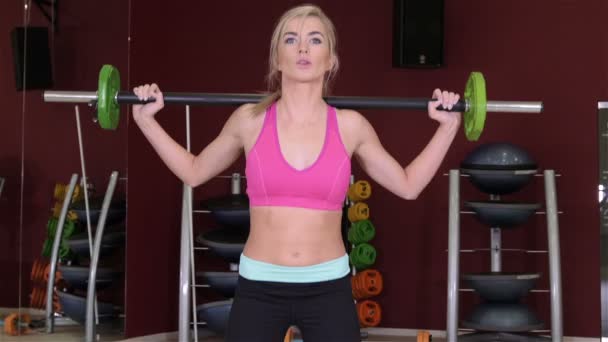 Жінка робить вправи плечової преси з ваговою планкою всередині спортзалу . — стокове відео