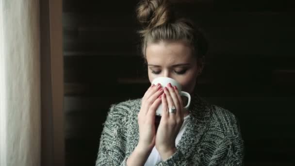 Žena doma pití kávy nebo čaje a usmívá se na kameru. — Stock video