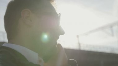 Mutlu genç işadamı ofisinin önünde oturan telefonda konuşuyor.