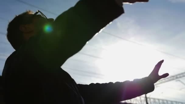 Silueta hombre de negocios levantando las manos sobre la ciudad borrosa en el fondo del atardecer . — Vídeo de stock