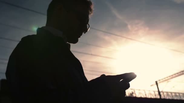 Портрет красивого молодого чоловіка, який надсилає текстове повідомлення, стоячи надворі . — стокове відео