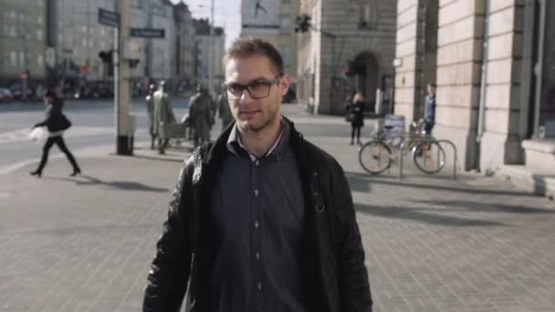 Retrato de un joven con anteojos caminando por las calles de la ciudad . — Vídeo de stock