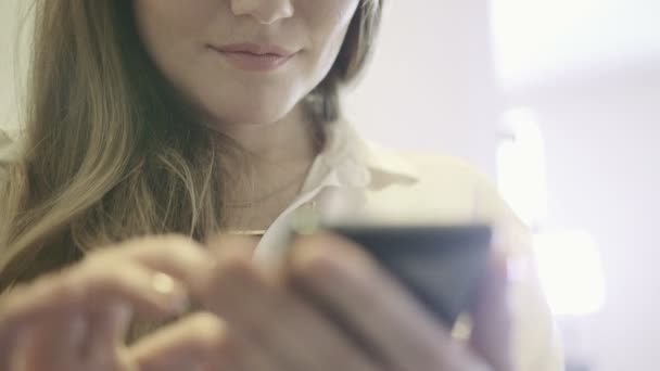 Jovem mulher sorrindo segurando um smartphone na mão e navegando na Internet . — Vídeo de Stock