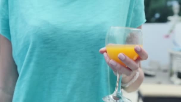 Жіноча рука тримає склянку з соком під час прогулянки біля басейну . — стокове відео