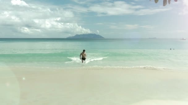 Šťastný muž na pláži na Seychelách, který vychází z moře. — Stock video