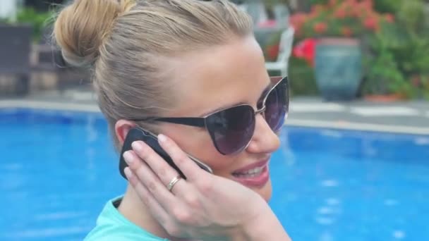 Giovane donna attraente utilizzando il suo telefono cellulare in vacanza vicino alla piscina . — Video Stock