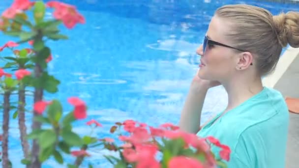 Junge attraktive Frau benutzt ihr Handy im Urlaub in der Nähe des Pools. — Stockvideo