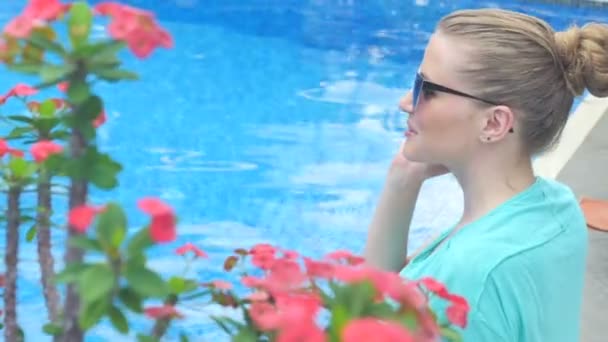 Young attractive woman using her cell phone in holidays near the pool. — Stok video