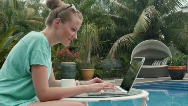 Retrato de uma jovem mulher na frente de um computador portátil ao lado de uma piscina . — Vídeo de Stock