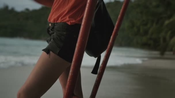Молодая женщина в шортах, стоящая одна на пляже на закате . — стоковое видео