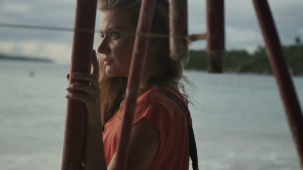 Giovane donna bionda in piedi da sola sulla spiaggia e guardando il tramonto . — Video Stock