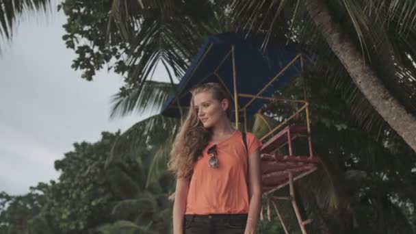 Νεαρό ξανθιά γυναίκα που στέκεται μόνη της στην παραλία και κοιτάζοντας το ηλιοβασίλεμα. — Αρχείο Βίντεο