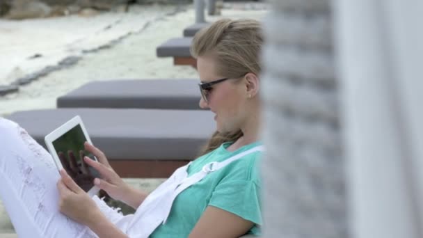 Gladlynt kvinna sitter i hotel solstol med digital tablet under semester. — Stockvideo