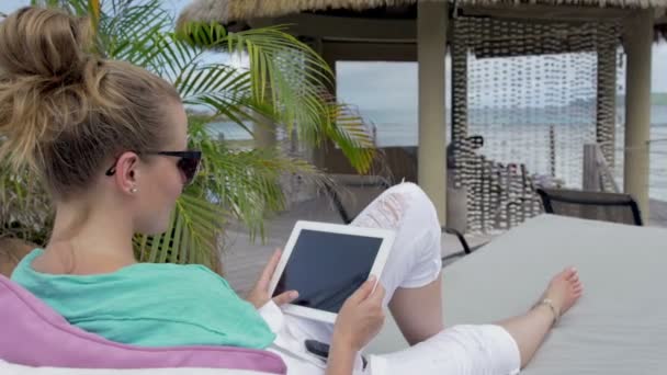 Gladlynt kvinna sitter i hotel solstol med digital tablet under semester. — Stockvideo