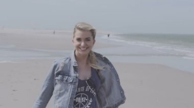 Eğleniyor denim ceket mutlu genç kadın yalnız plajda zaman.