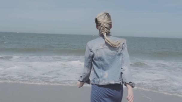 Šťastná mladá žena v džínové bundě zábavu čas na opuštěné pláži. — Stock video