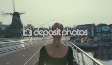 Holland, ağır çekim bir köprü üzerinde günbatımında çalışan bir kadın silueti arkadan görünüm.