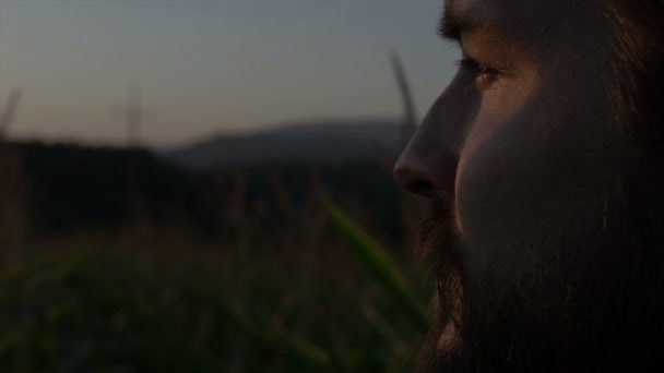 Nahaufnahme eines gutaussehenden Mannes mit Bart mit Naturlandschaft im Sonnenuntergang. — Stockvideo
