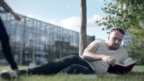 Молодая романтическая пара, лежащая в парке и читающая книгу . — стоковое видео