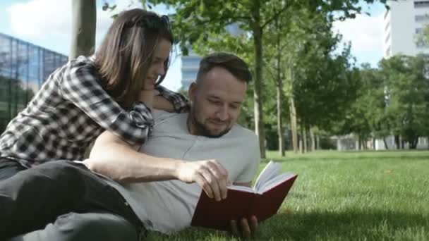 Junges romantisches Paar verbringt Zeit im Park und liest Buch. — Stockvideo