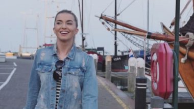 Limanda güneşli Sonbahar/Bahar günü yürüyen güzel neşeli sarışın kadın.