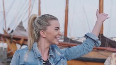 Limanda yürüyüş ve birine sallayarak güzel neşeli sarışın kadın.