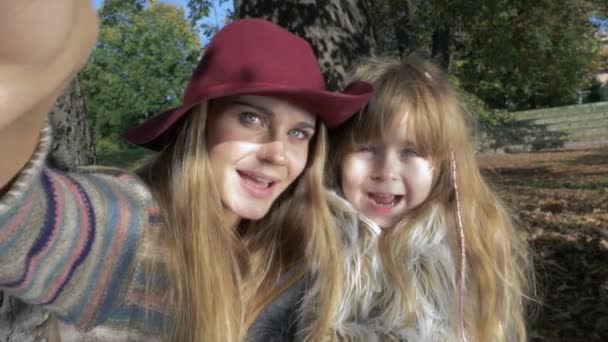 Mutter umarmt ihre süße Tochter in einem sonnigen herbstlichen Park im Freien. — Stockvideo