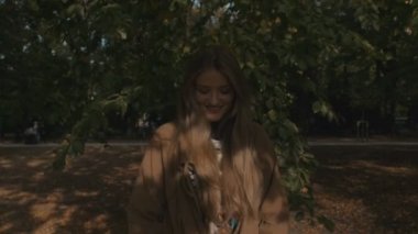 Kameraya bakarak ve gülümseyen sonbahar Park'ta yürüyordunuz genç güzellik.