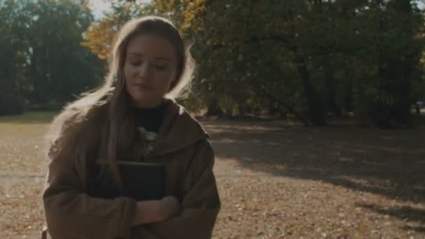 Glückliche Frau spaziert fröhlich durch herbstlich sonnigen Park. — Stockvideo