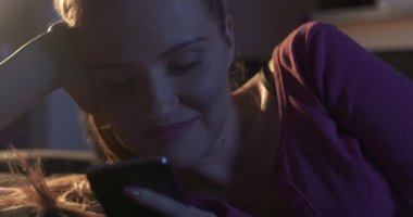 Gece kanepede yatan süre Smartphone kullanarak çekici genç kadın.